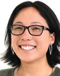 An Asian woman with a dark bob wearing glasses and silver earrings smiles.