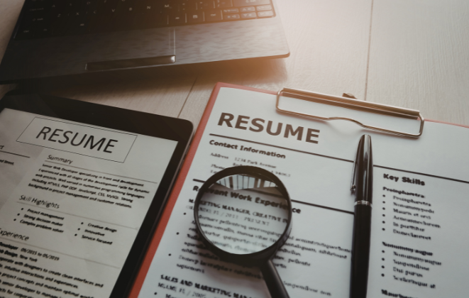 Resumes and a magnifying glass
