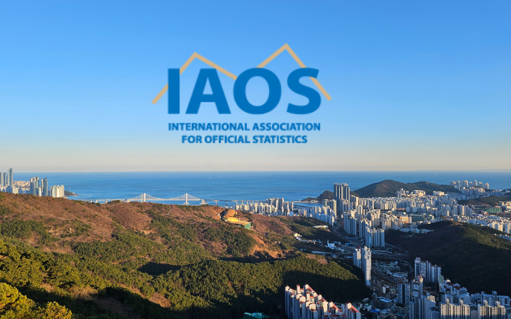 IAOS logo that has a yellow line behind the letters IAOS. It's sitting in the front of a drone shot of Busan Korea