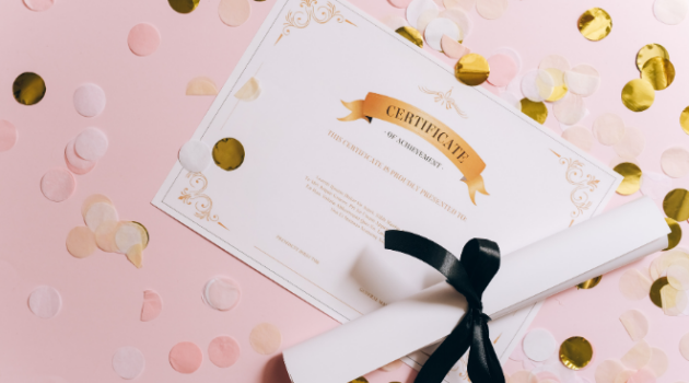 A certificate and a rolled up piece of paper tied with a ribbon