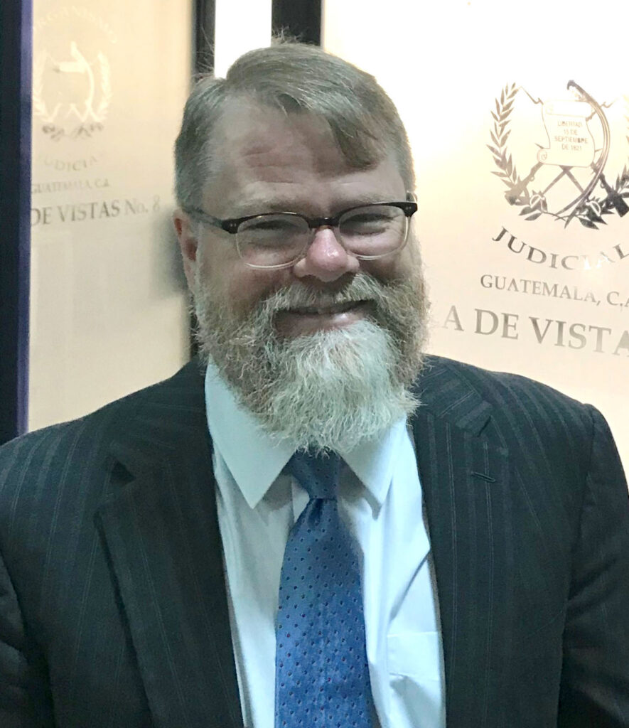 Short hair, glasses, white beard and mustache.