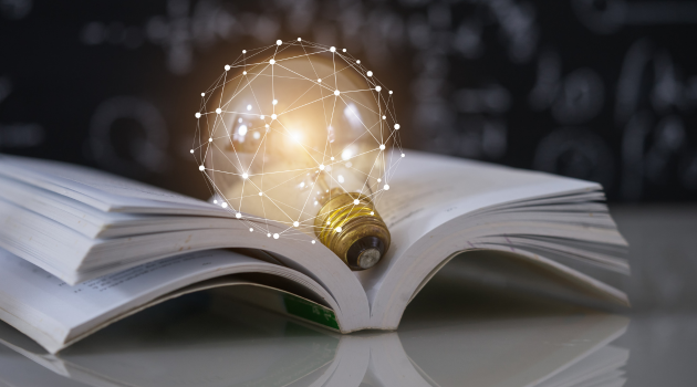 A lightbulb with abstract tech patterns around it, sitting on top of an open text book.